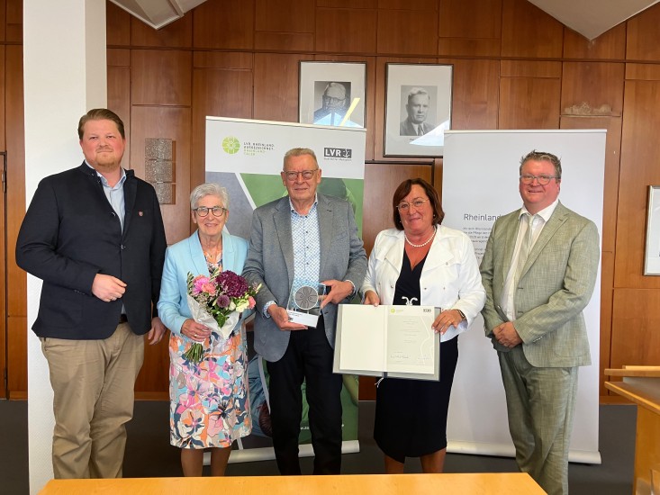 Ein Gruppe festlich gekleideter Menschen. In der Mitte steht Hans-Gerd Vrede mit einer Trophäe in der Hand.